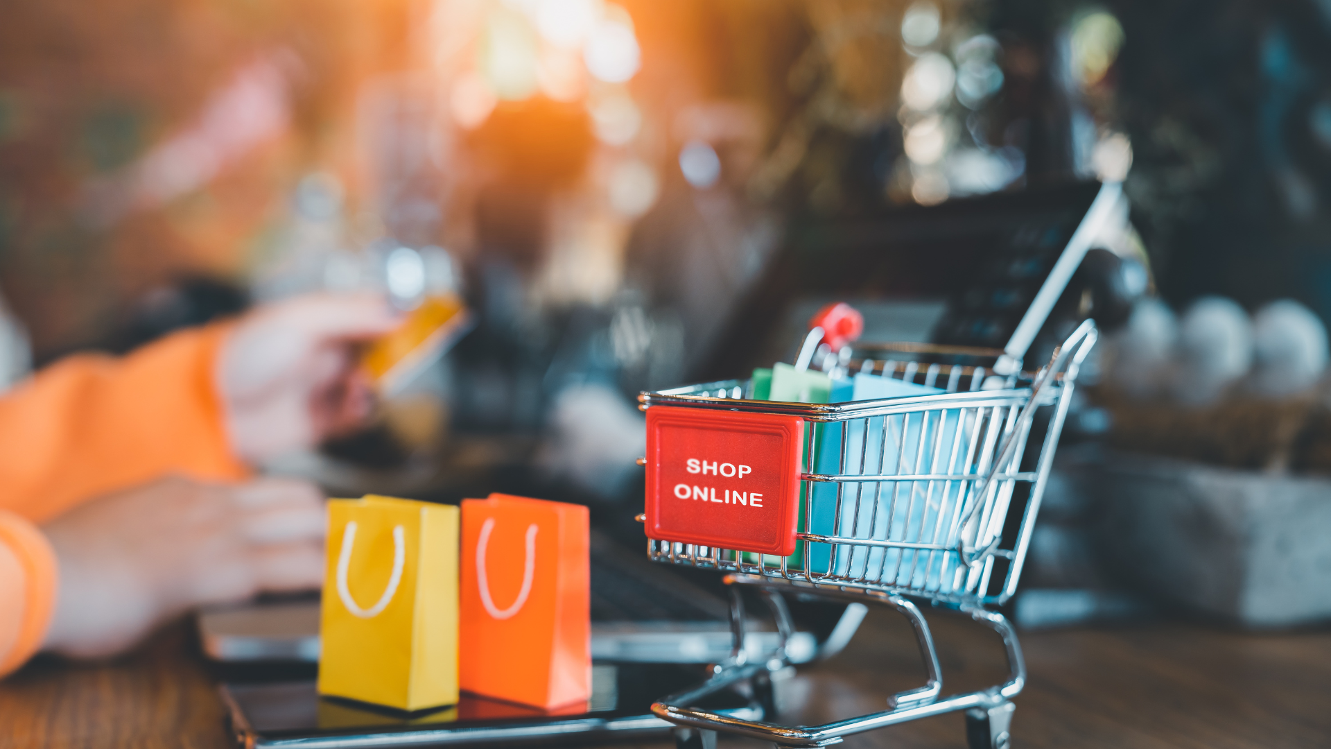 Un piccolo carrello della spesa con sacchetti colorati posizionato su un laptop mentre un utente procede al pagamento, rappresentando il supporto operativo per il Digital Export e le vendite online.