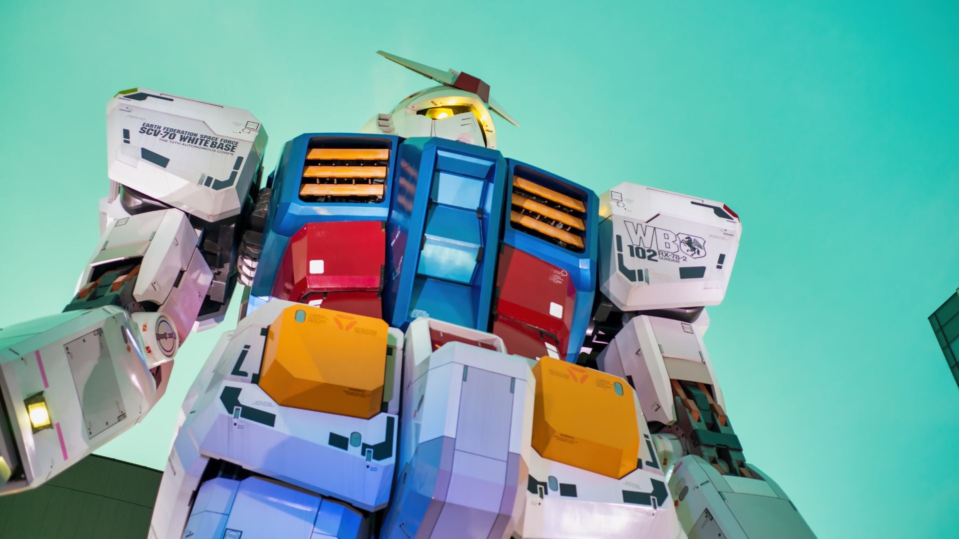 Inquadratura dal basso della maestosa statua gigante del Gundam RX-78-2 a Odaiba, Tokyo, simbolo della cultura mecha e meta imperdibile dell'itinerario Otaku di Hidden Japan.