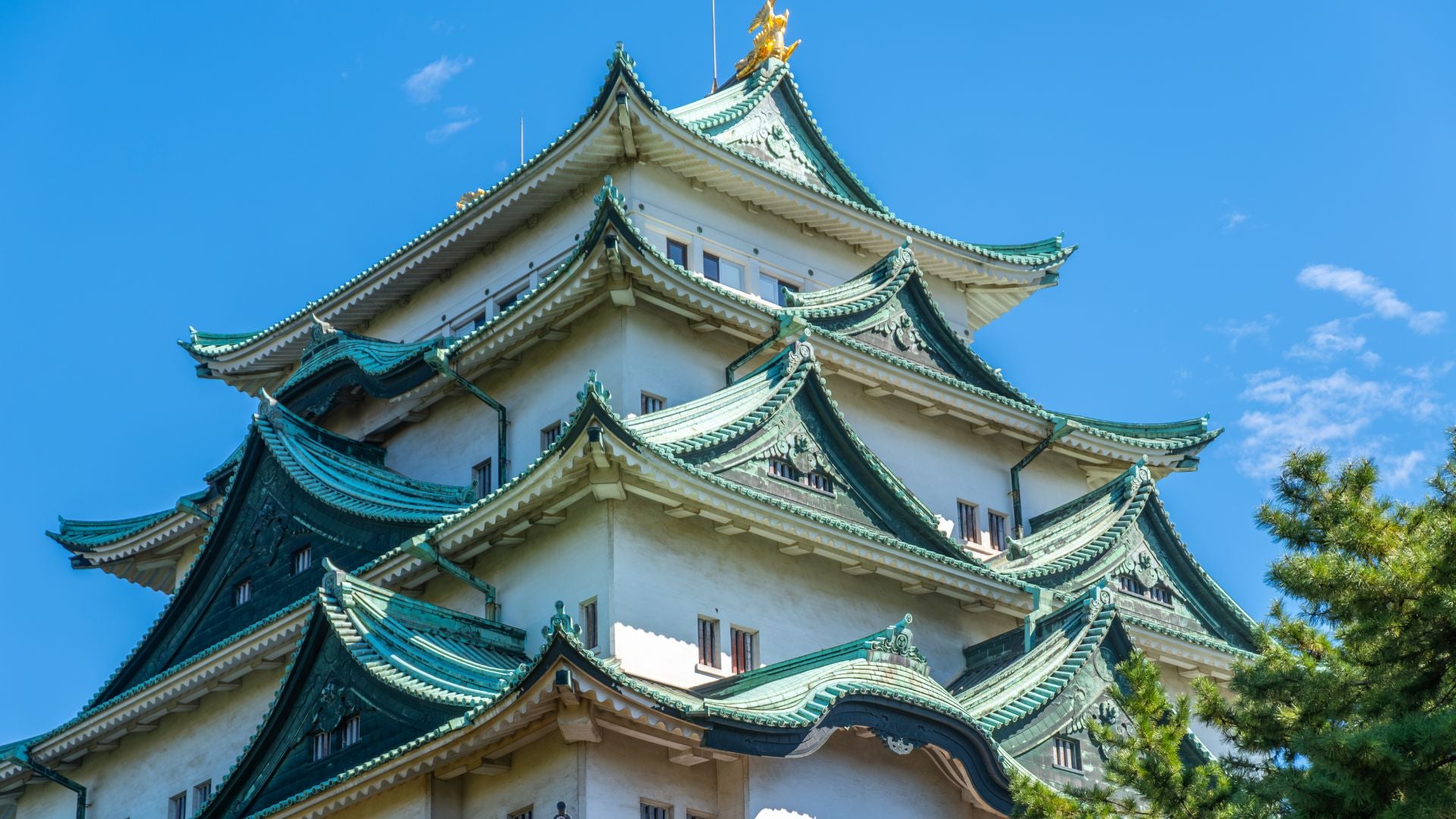 Il monumentale Castello di Nagoya con i suoi tetti verdi e dettagli dorati sotto un cielo azzurro; Hidden Japan propone itinerari storici alla scoperta dei castelli e dell'architettura tradizionale del Sol Levante.
